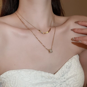 Detail view of 18k gold plated double layered necklace with zircon cylinder pendant
