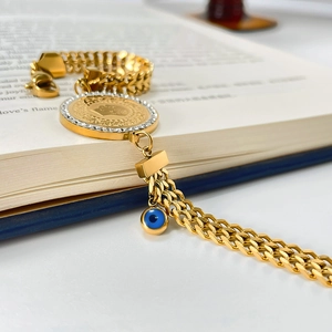 Macro shot of gold snake chain bracelet with crystal coin pendant and blue evil eye charm