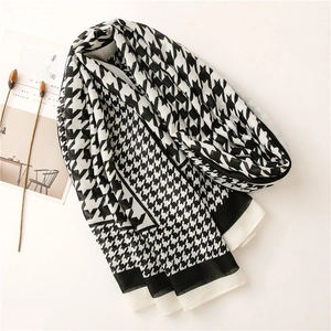 Detailed texture of black and white houndstooth scarf with elegant flat-edge stitching
