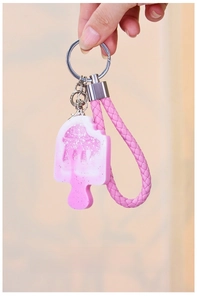 Close-up of pink ice cream silicone mold keychain with glitter texture and woven strap