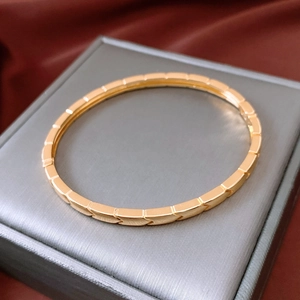 Détail d'un bracelet jonc plaqué or 18 carats à motif flèche sur un écrin gris chic