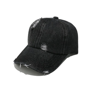 Close-up of distressed ripped details on a black washed denim baseball cap crown