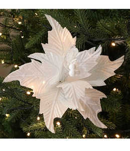 Close-up of a white velvet Christmas flower with shimmering glitter on a festive tree