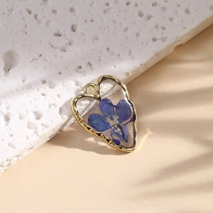 Golden heart-shaped earring featuring a preserved blue daisy flower inside clear resin