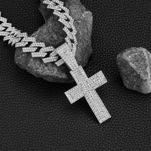 Silver iced out Cuban chain with rhinestone cross pendant on dark volcanic rocks