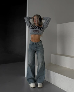 Détail d'un jean bleu clair taille haute à jambes larges et d'un sweat-shirt court gris