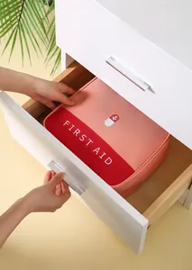 Portable first aid kit stored in a white wooden drawer for home medical storage