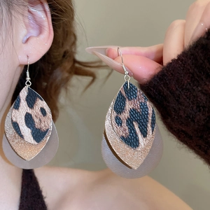 Macro detail of triple-layered leopard print leather teardrop earrings with silver hooks