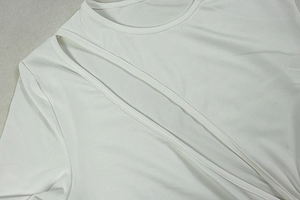Detail of white round neck dress with diagonal hollow-out design and pleated fabric texture