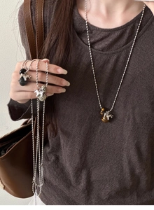 Detailed view of silver bead chain necklace with tiger eye stone bell pony pendant