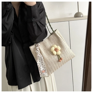 Detailed view of beige woven bucket bag with floral charm and printed scarf accessory