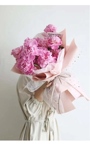 Detail of pink peony bouquet with gold star mesh wrapping paper held by a model