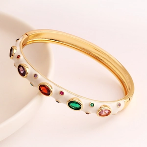 Detailed macro shot of a gold-plated colorful zircon bangle with white enamel inlay