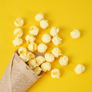 Macro detail of realistic spherical popcorn models pouring from a kraft paper cone