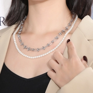 Détail d'un collier double rang avec perles blanches et chaîne argentée nouée