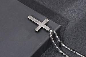 Macro view of vintage silver cross pendant with brushed metal texture and box chain