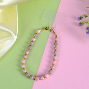 Detail of pink zebra stone phone wrist strap with golden clasp and beads on silk