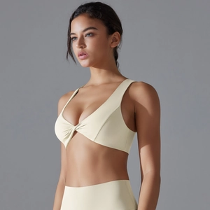 Detailed view of the front knot design on a cream high-stretch sports bra for yoga