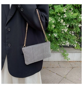Macro shot of a silver rhinestone envelope bag with a delicate gold metal chain strap