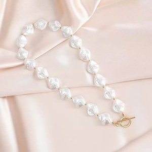 Macro detail of Baroque pearl necklace with golden metal spacers and elegant toggle clasp