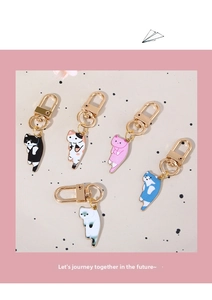 Close-up of five colorful enamel cat pendants with gold spring buckles on a beige background