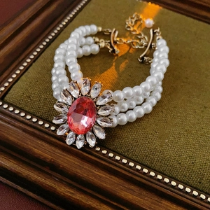 Détail d'un collier de perles multicouches avec une pierre rose ovale sur velours