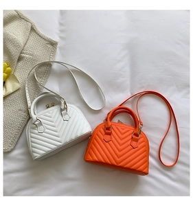 Close-up of white and orange leather shell bags with premium chevron quilted texture details