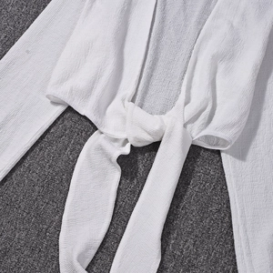 Détail du cardigan blanc à nouer avec tissu gaufré texturé et cordon de serrage au col