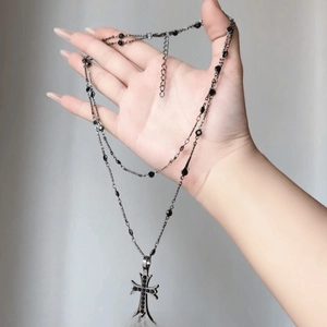 Detail of layered cross pendant necklace with black beads and vintage silver finish