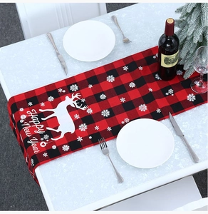 Detail van rood-zwarte geruite kersttafelloper met witte rendier- en sneeuwvlokkenpatronen