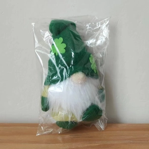 Close-up of Saint Patrick's Day gnome plush in plastic packaging on a wooden surface