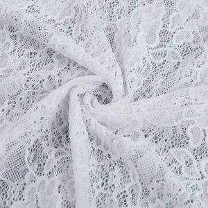 Dettaglio del tessuto in pizzo floreale bianco con ricami delicati e trama fine