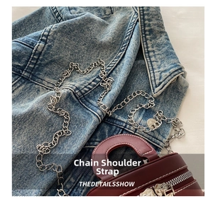 Détail macro du sac en cuir bordeaux avec chaîne argentée et double fermeture éclair