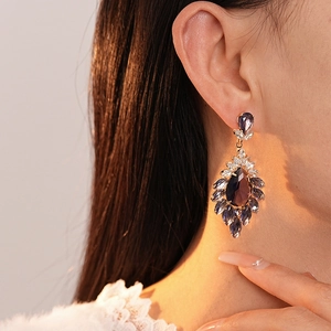 Close-up of a model wearing purple teardrop crystal earrings with gold plating