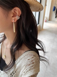 Close-up of elegant teardrop mother-of-pearl earrings and silver ear cuff on model