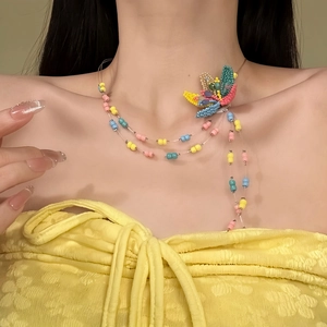 Detailed macro view of vibrant dopamine glass beaded flower necklace worn by a female model