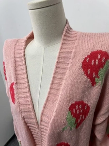 Detail shot of strawberry jacquard pattern and ribbed knit texture on pink cardigan