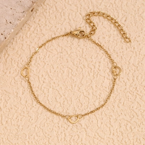 Detail of 14K gold plated heart charm bracelet with adjustable lobster clasp on stone