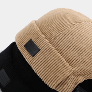 Close-up of corduroy texture and leather patch detail on vintage docker caps in khaki and black