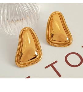 Detail of 18K gold irregular geometric earrings with textured grooved edges and polished finish