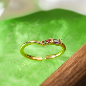 Macro detail of adjustable gold plated ring set with green, red and purple zircons