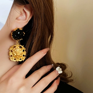 Close-up of vintage lion head earrings with black circular accents and golden finish