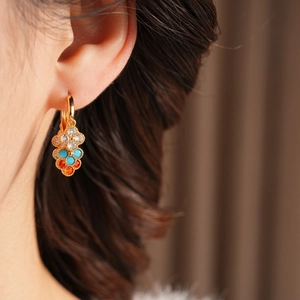 Close-up of gold flower earrings with colorful zircon stones worn on a model