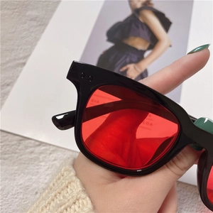 Detail of black square frame sunglasses featuring red lenses and silver rivets decoration