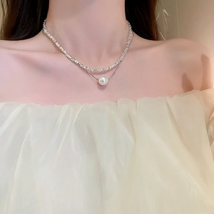 Close-up of double layer silver-tone necklace with pearl on neck with silk dress