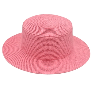 Nahaufnahme der geflochtenen Textur eines rosa flachen Strohhuts mit kleiner Krempe