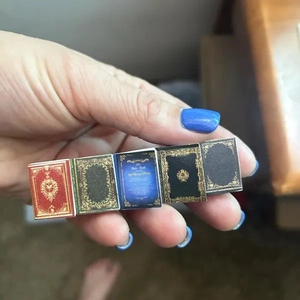 Detailed close-up showing five miniature vintage books held by hand to show compact size