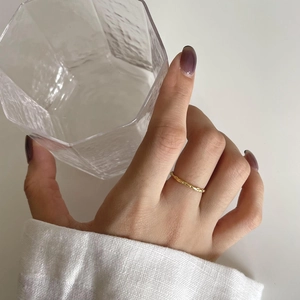 Elegant gold wavy minimalist ring with hand-hammered texture worn by model on finger