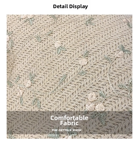 Gros plan sur un tissu tricoté beige avec broderies délicates de fleurs et vignes