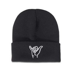 Détail du bonnet en maille noire avec une broderie blanche en forme de geste Shaka